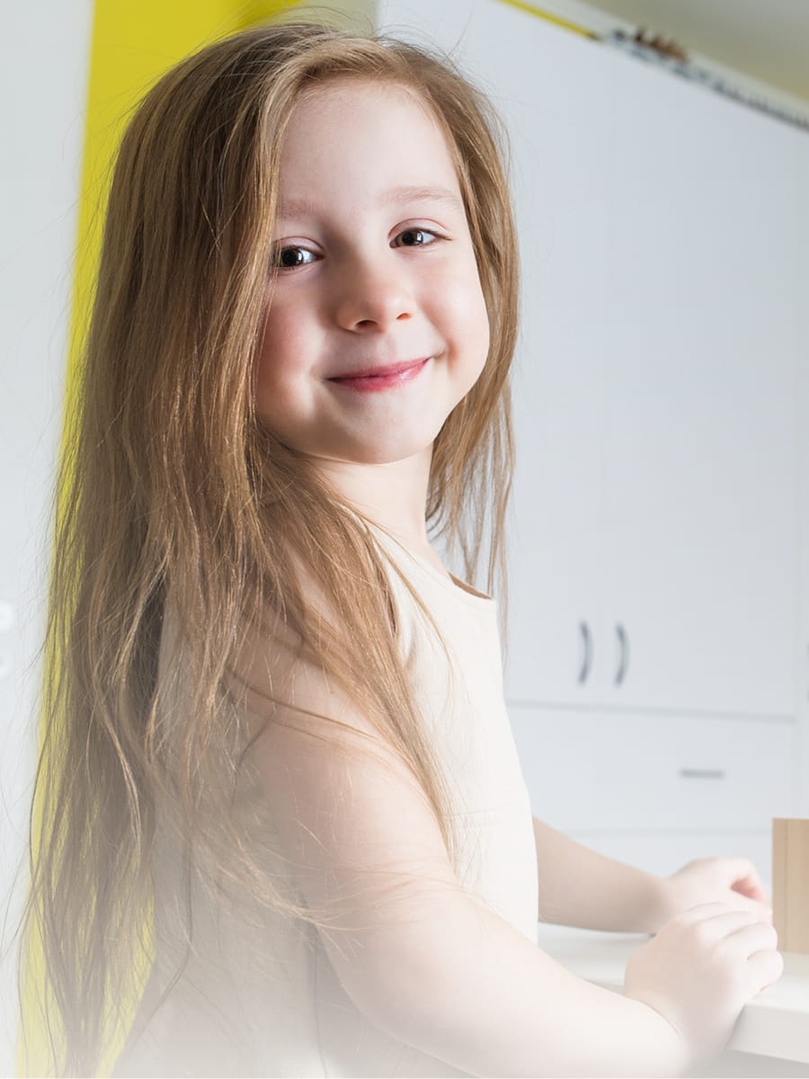 Foto Mädchen mit langen Haaren, sitzt am Spieltisch und lächelt